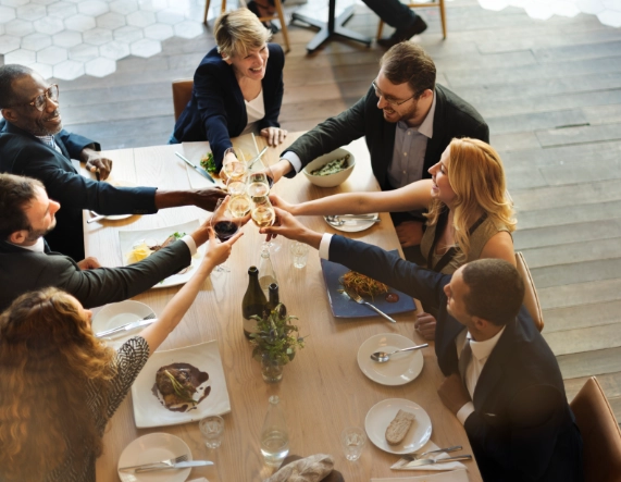 Business people at table cheers during corporate event